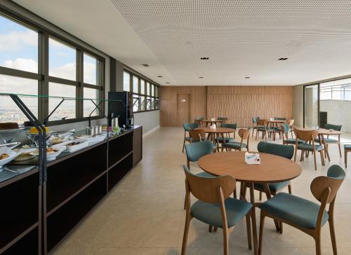 a restaurant with tables and chairs and windows at Palazzo Torquetti in Belo Horizonte