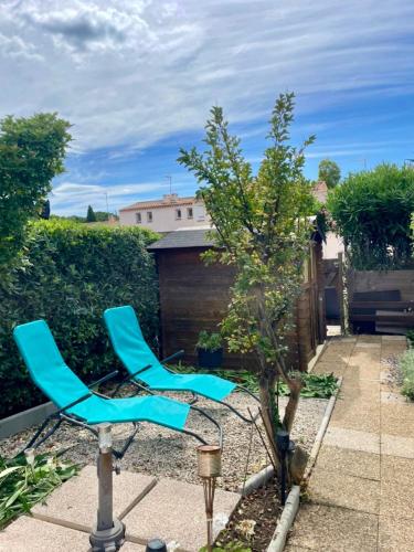 deux chaises bleues assises à côté d'un arbre dans l'établissement Maison Paisible - 4pers - Histoire de clés, au Cap d'Agde