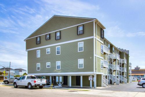 a large green building with cars parked in a parking lot at Driftwood Villa 101 by Carolina Beach Realty in Carolina Beach
