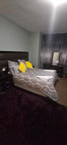 a bedroom with a bed with two yellow pillows at Nestle -me in Krugersdorp