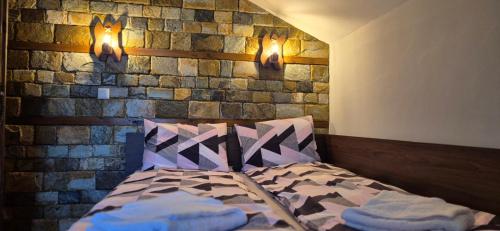 a bed in a room with a brick wall at Къща за гости Брязово in Ribarica