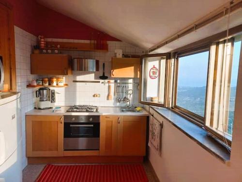 a kitchen with a stove and a sink and two windows at Appartamenti vistAmare - Casacromia - in Vibonati