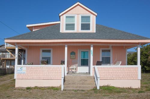 a small pink house with a porch and chairs at Hunnicutt House by Carolina Beach Realty in Kure Beach