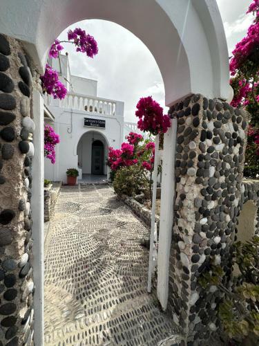 an archway leading to a white building with pink flowers at Calypso Heaven in Santorini