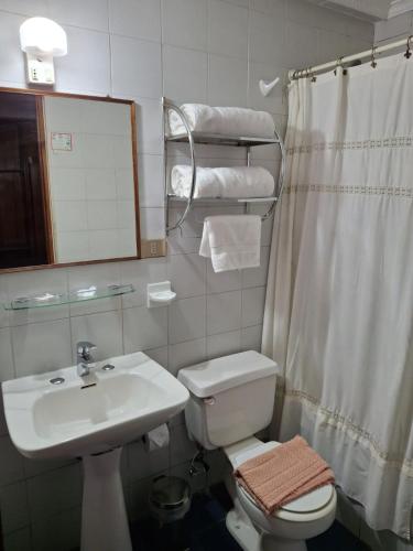 a bathroom with a sink and a toilet and a mirror at Hotel Escorial in La Serena