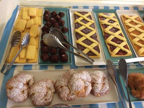 a table topped with trays of pastries and desserts at Hotel Lady Mary in Milano Marittima