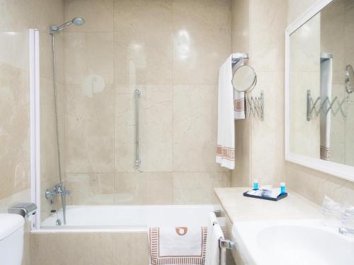 a bathroom with a shower and a tub and a sink at Hotel Pasarela in Seville