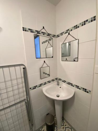 a white bathroom with a sink and a mirror at Appartement F1 in Mauriac