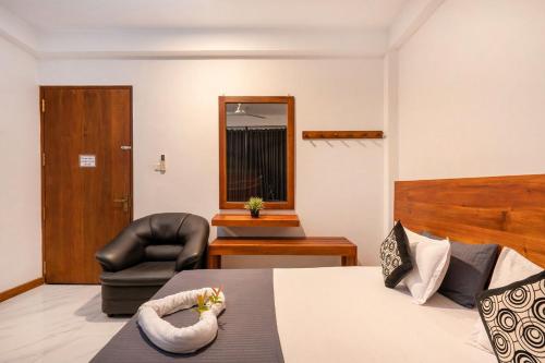 a room with a bed and a chair and a mirror at cmb apartments in Negombo