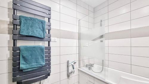 La salle de bains est pourvue d'une douche et de serviettes bleues. dans l'établissement Chez Le General - Charmant T2, à Mulhouse