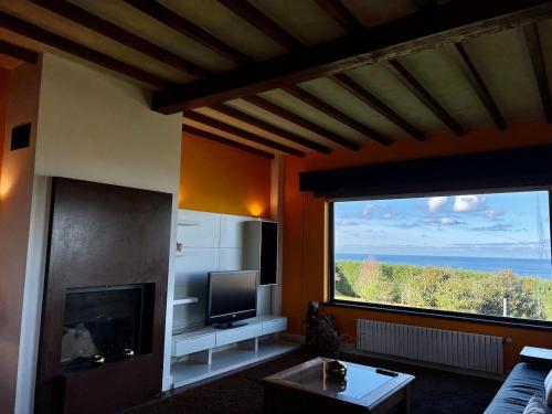 a living room with a fireplace and a large window at Magnífica villa mirando al mar in Suances