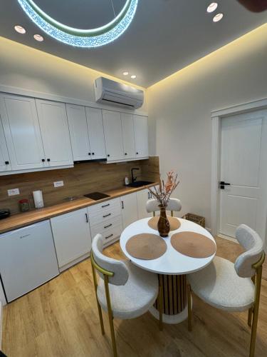 a kitchen with white cabinets and a table and chairs at Silver Stone Suites in Gjirokastër