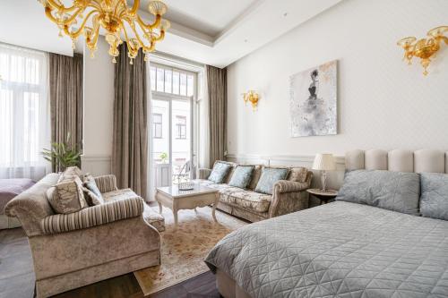 a bedroom with a bed and a couch and a chandelier at Basilica view prime apartment with free parking in Budapest