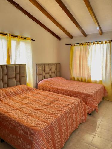 a bedroom with two beds with orange sheets at Casa Acogedora y Amoblada in Buga