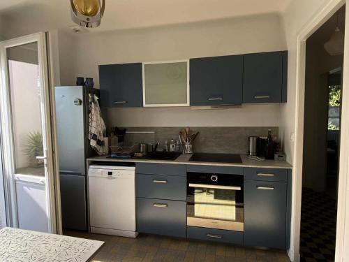 La cuisine est équipée de placards bleus et d'un réfrigérateur. dans l'établissement Résidence Lus-73-pornichet - PORNICHET - SAINTE MARGUERITE MAE-0001, à Pornichet