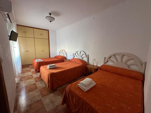 a hotel room with two beds with orange sheets at Hostal J&C in Olula del Río