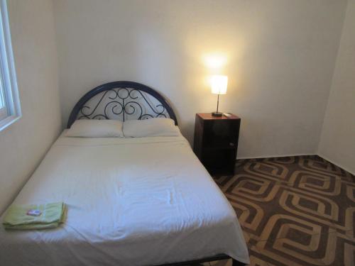 a bedroom with a bed with a lamp on a night stand at surf la bamba in Dolores Miramar