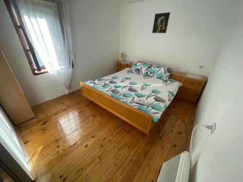 a small bedroom with a bed and a wooden floor at Kuća Mitića in Pirot