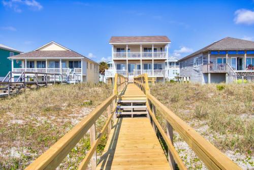 a wooden boardwalk leading to houses on the beach at Next Time Down by Carolina Beach Realty in Kure Beach