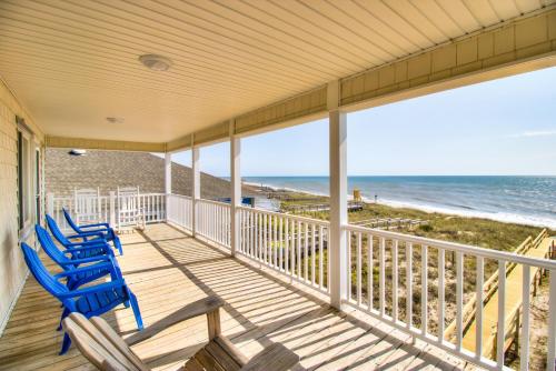 a porch with blue chairs and the ocean at Next Time Down by Carolina Beach Realty in Kure Beach
