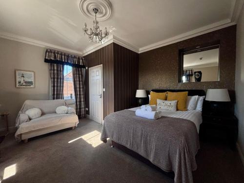 a bedroom with a bed and a couch and a mirror at The Lodge in Kings Lynn