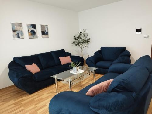 a living room with two blue couches and a table at Tolj apartman in Ljubuški