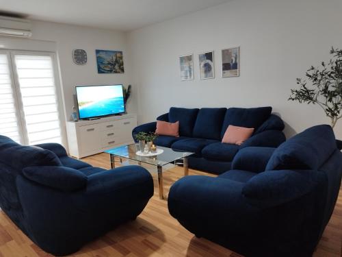 a living room with blue couches and a tv at Tolj apartman in Ljubuški
