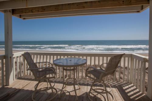 a patio with a table and chairs and the ocean at Ocean Dunes 1001 by Carolina Beach Realty in Kure Beach