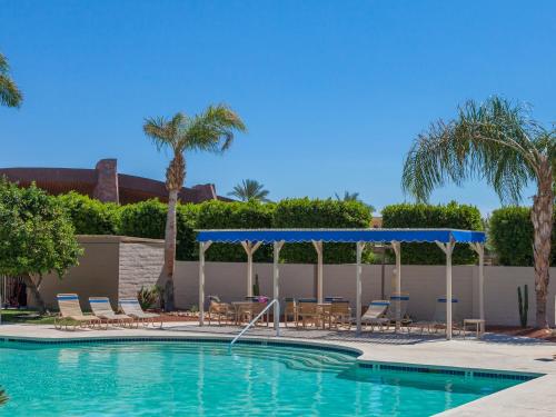 a swimming pool with chairs and a gazebo at Downtown Winner at Plaza Villas by ACME House Company in Palm Springs