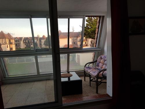 a room with a balcony with a chair and a window at studio front de mer in Ouistreham