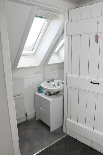 a white bathroom with a sink and a skylight at Birch Cottage in Laggan