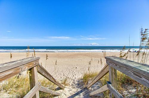 Blick auf einen Strand mit zwei Holzbänken in der Unterkunft Ocean Oasis by Carolina Beach Realty in Carolina Beach