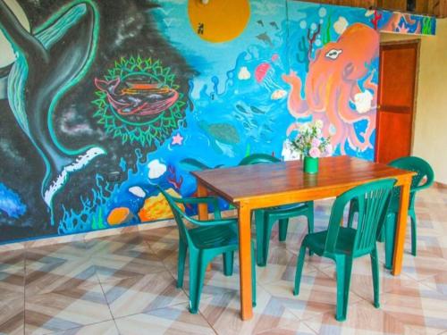 un comedor con mesa, sillas y un mural en Posada Las Palmeras, en Bahía Solano