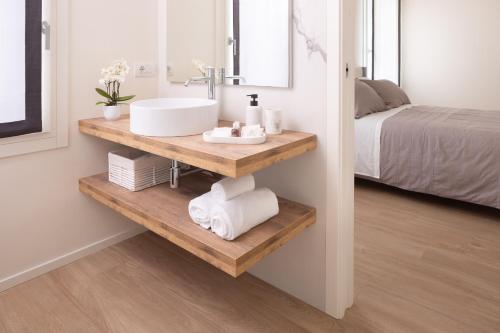 ein Badezimmer mit einem Waschbecken auf einem Holzregal neben einem Bett in der Unterkunft Bellavista Holiday House in Valdobbiadene