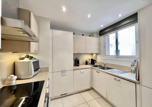 une cuisine avec des armoires blanches et un micro-ondes dans l'établissement Appartement de deux chambres à coucher près de la Croisette à Cannes, à Cannes