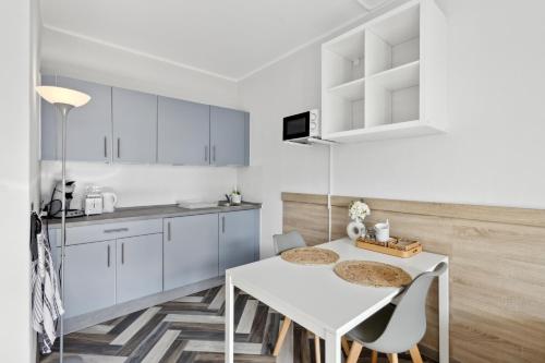 a kitchen with white cabinets and a white table and chairs at Sali Homes - Ferienwohnung in Kevelaer - Comfort in Kevelaer