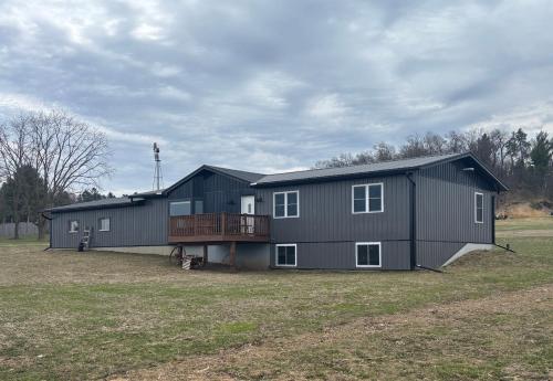 a large black house with a deck on a field at Comfortable Country Home in Sparta