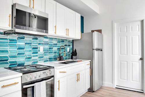 a kitchen with white cabinets and blue tile on the wall at Urban Nest #2 Vibrant suite downtown by Proctors in Schenectady