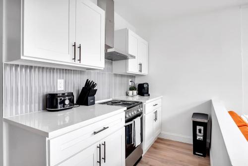 a kitchen with white cabinets and a stove top oven at Urban Nest #3 Bright loft steps to Proctors in Schenectady