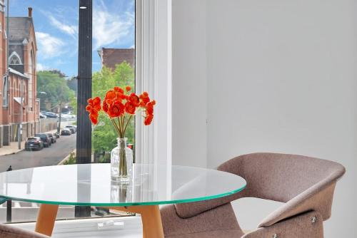 a glass table with a vase of flowers and a chair at Urban Nest #3 Bright loft steps to Proctors in Schenectady