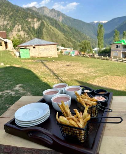een dienblad met eten, friet en ketchup op tafel bij Luxury Timber Resorts and Hotels Cottages in Upper Neelum, Keran, AJK in Chak