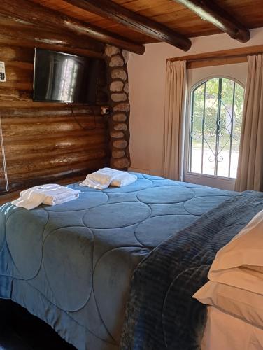 a bedroom with a blue bed with a tv on the wall at Posada de Nono in Nono