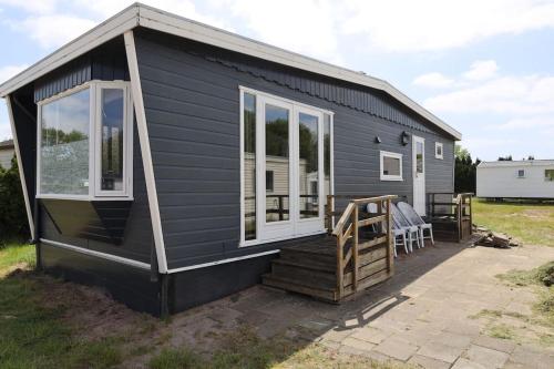 a black tiny house with a porch and windows at Nette chalet nabij het bos in Anloo