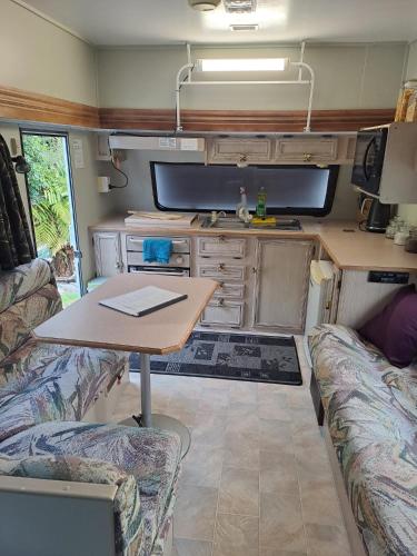 a living room with a table and a tv in a caravan at Koru Beachfront Holiday Cabins & Hot Tub in Barrytown