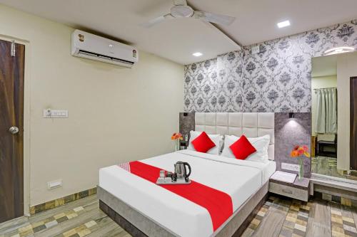 a bedroom with a large white bed with red pillows at Collection O Hotel Raj Palace in Vadodara