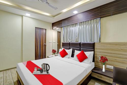 a bedroom with a large bed with red pillows at Collection O Hotel Raj Palace in Vadodara