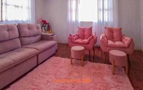 a living room with pink furniture and pink chairs at Cobertura com Vista e Conforto no RS in Santo Ângelo