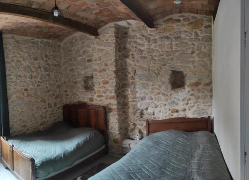 a bedroom with two beds in a stone wall at Maison dans les Cévennes in Bessèges