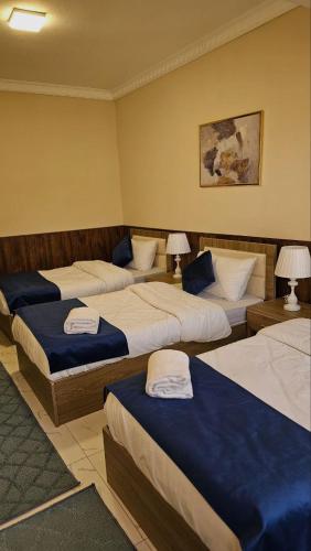 a hotel room with three beds and two lamps at VIP Hotel Amman in Amman