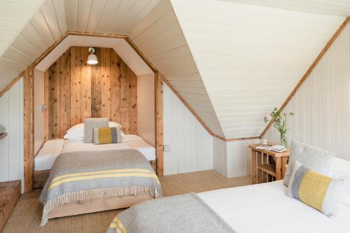 a room with three beds in a attic at Broomfeild Bothy Comes with a Sauna in Boat of Garten